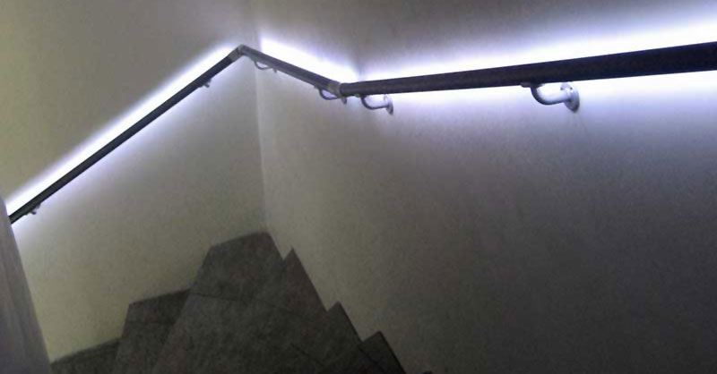 Beleuchteter Wandhandlauf an gewendelter Treppe